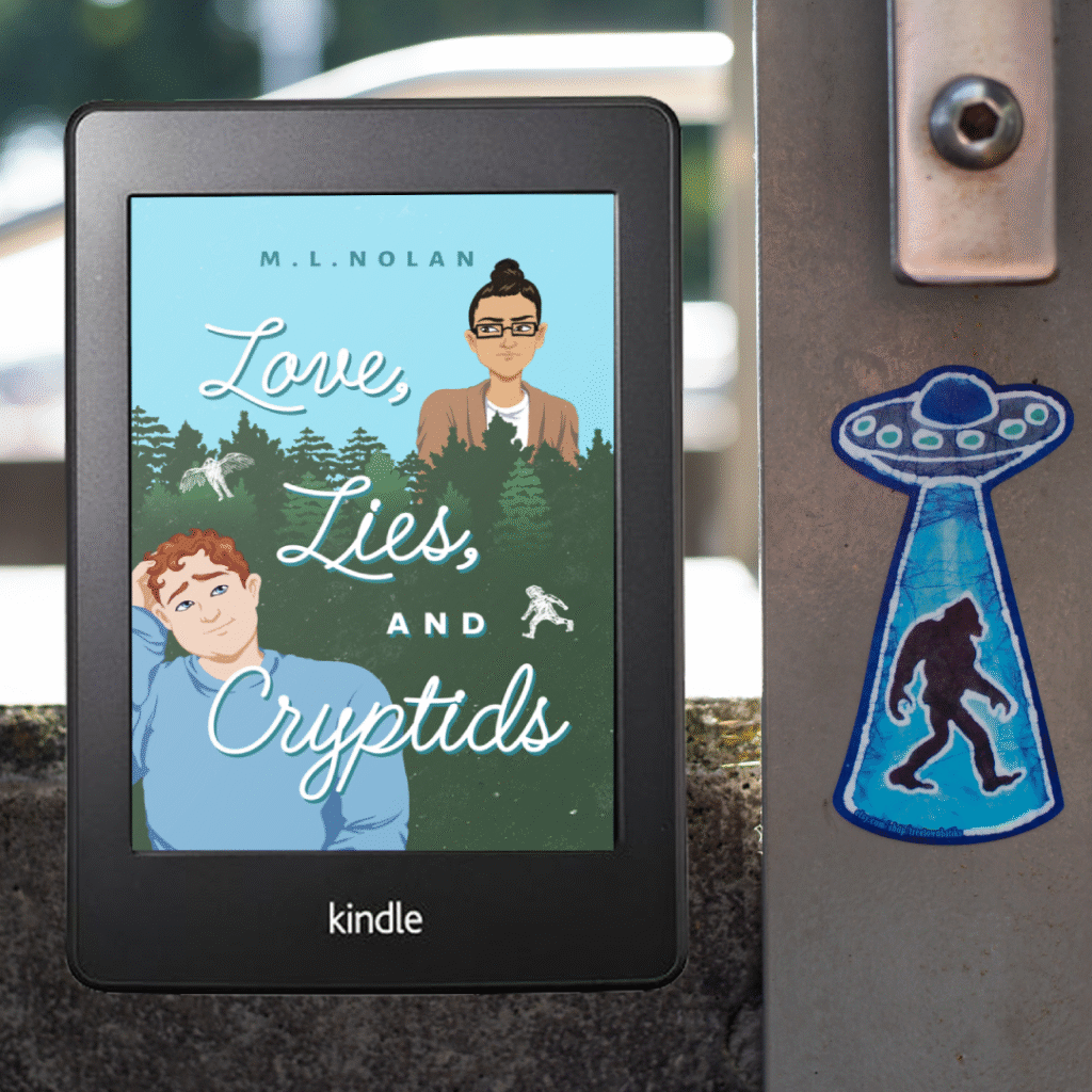 A photo of Love, Lies, and Cryptids' cover on a Kindle. The background is a concrete wall beside a piece of metal with an illustrated sticker stuck on it. The sticker is a blue UFO, flying saucer, beaming up a silhouette of Bigfoot.